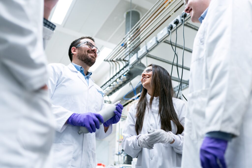 Engagement course photo - scientists talking in lab coats with hand and eye protection